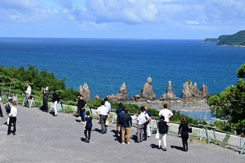 国の名勝・天然記念物「橋杭岩」も望むことができる現地周辺を視察する説明会の参加者ら（２８日、和歌山県串本町くじの川で）