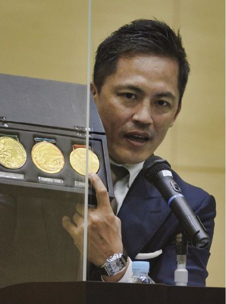 オリンピックで獲得した三つの金メダルを披露する野村忠宏さん（和歌山県田辺市扇ケ浜で）