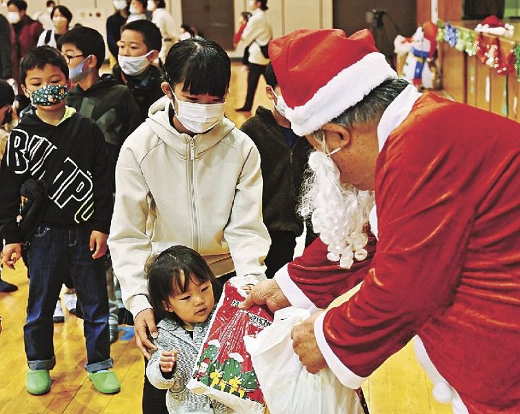 関係者が扮したサンタクロースからプレゼントをもらう子どもたち（１２日、和歌山県串本町串本で）