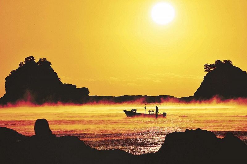 朝日に照らされ黄金色になった海霧の中を進む漁船（２９日午前６時５４分、和歌山県串本町田原で）