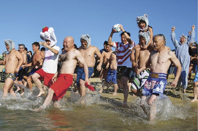 勢い良く海に駆け込む新春初泳ぎの参加者（和歌山県の田辺市扇ケ浜で）