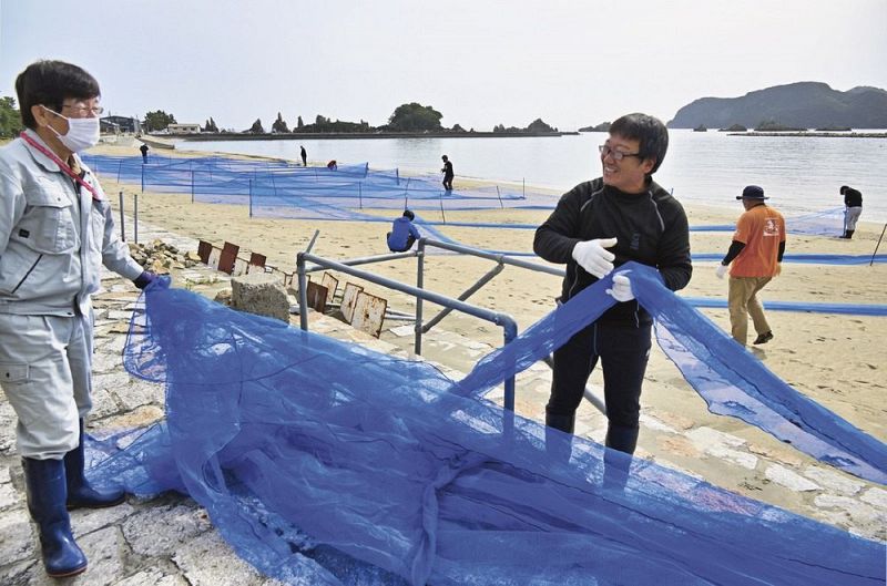 橋杭海水浴場の防砂ネットを外す関係者（和歌山県串本町くじの川で）