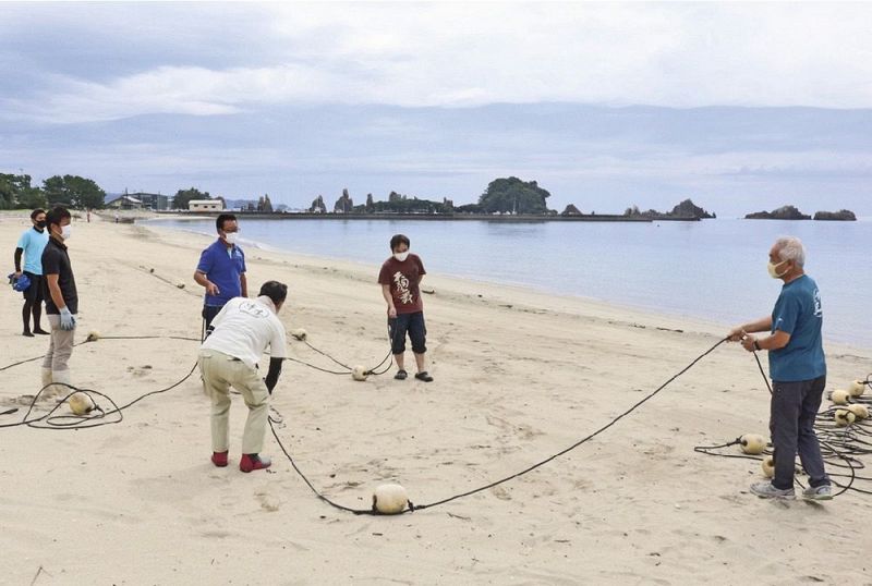 海開きに向けてブイを設置する観光協会関係者ら（１３日、和歌山県串本町くじの川で）