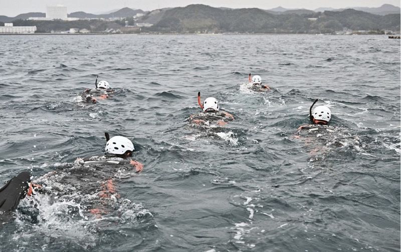 紀伊大島から対岸の橋杭海水浴場を目指して泳ぐ潜水隊員（１０日、和歌山県串本町大島沖で）