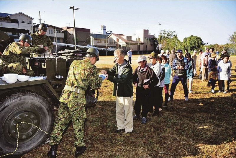 自衛隊員から出来たての豚汁を受け取る住民ら（３日、和歌山県みなべ町埴田で）