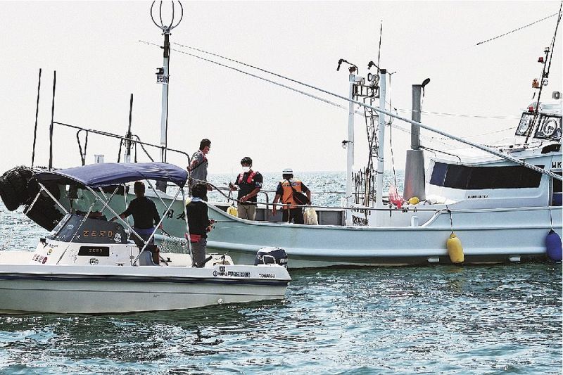 プレジャーボート（手前）に乗って釣りをする人に啓発物を渡す海上安全指導員ら＝田辺湾で