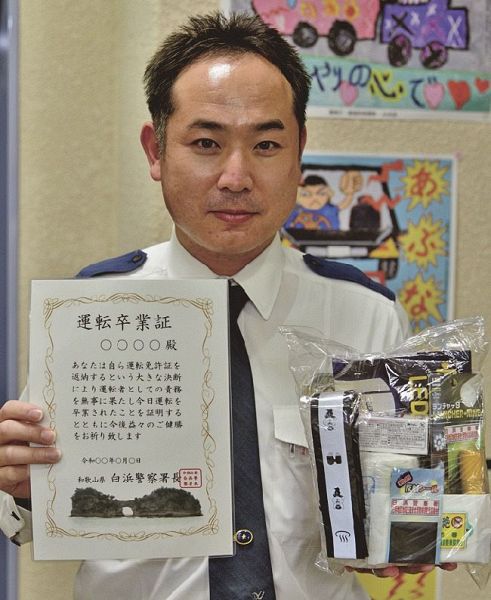 運転卒業証や記念品を持つ、白浜署交通課の田中康裕巡査部長（和歌山県白浜町で）