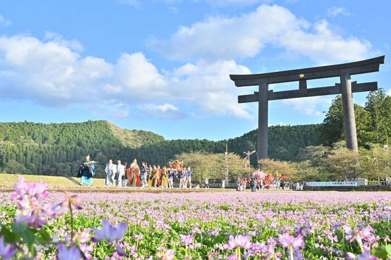 大鳥居をくぐり、周囲にレンゲソウが咲き乱れる御幸道を通って大社に戻る行列