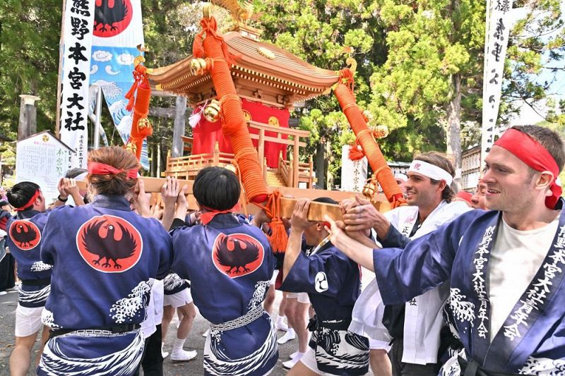 力を合わせてみこしを担ぐ氏子と外国人