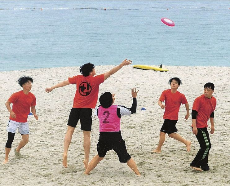 白良浜でフライングディスクを追いかける選手（和歌山県白浜町で）