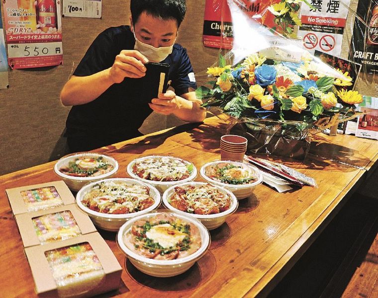 日替わりメニューを投稿するため、スマホで写真撮影する稲垣基さん（和歌山県田辺市湊で）