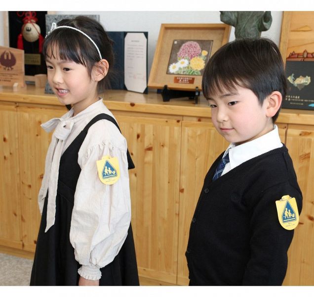 黄色いワッペンを肩に笑顔を見せる新小学１年生の池田莉心さん（左）と岩﨑仁希君＝４日、和歌山県田辺市東山１丁目で