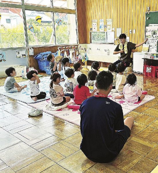 手遊びをする職員と子どもたちの様子を見学する小竹舷貴さん（手前）＝和歌山県御坊市塩屋町で