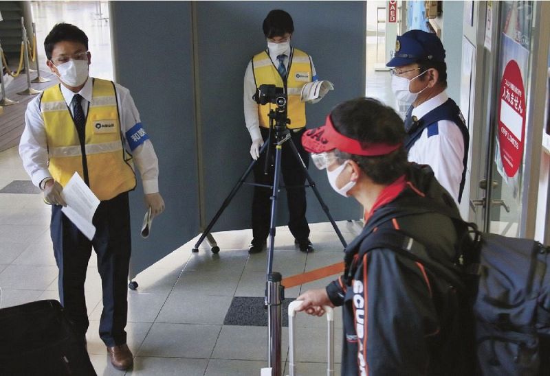 東京からの搭乗客を検温したり、チラシを配ったりする県職員（１日、和歌山県白浜町の南紀白浜空港で）