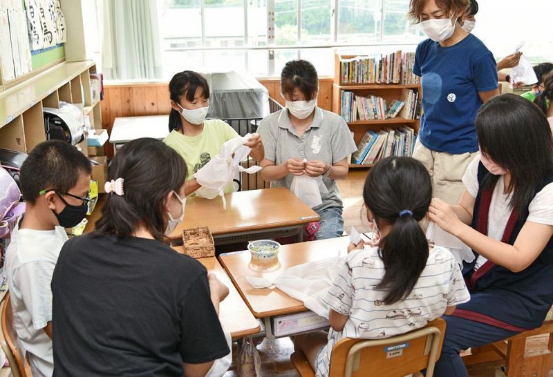 布を輪ゴムで縛るなどする児童と保護者（和歌山県田辺市龍神村福井で）