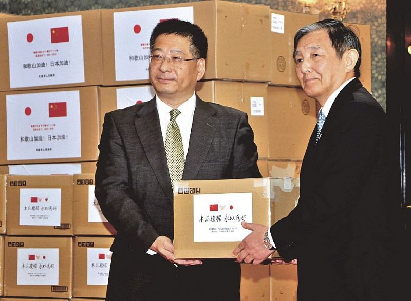 中国駐大阪総領事館の何振良総領事（左）から新型コロナウイルス感染症の対策の医療用資材の寄贈を受ける仁坂吉伸知事＝和歌山県庁で