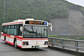 迂回路が新しくなったことを受けて、運行を一部再開した発心門王子行きのバス。写真奥が落石で通行止めとなった国道１６８号の斜面（２２日、和歌山県田辺市本宮町で）